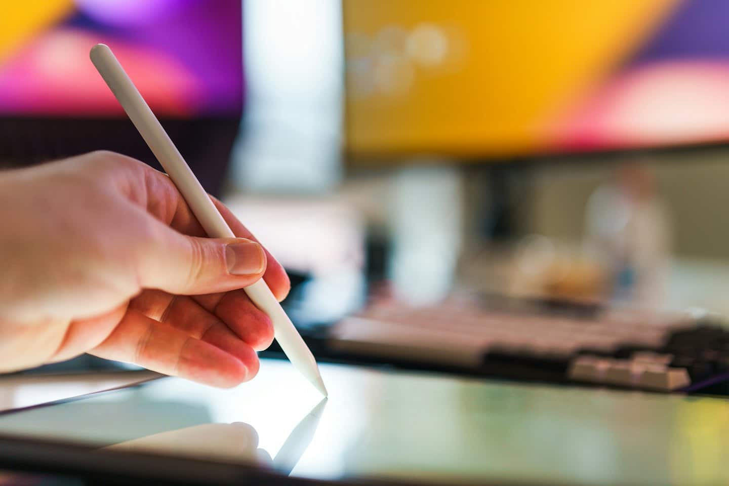 Hand holding a digital pen interacting with a tablet screen.
